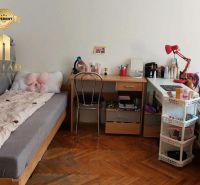 Student room in a one-room apartment with a wooden decor floor and simple furniture.