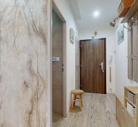 A hallway in a 3-room apartment with a wooden decor floor and light furniture.