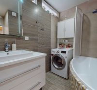 A bathroom in a 3-room apartment with a bathtub, a sink, and a washing machine.