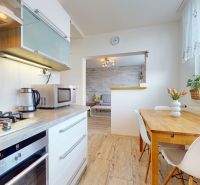 A kitchen in a 3-room apartment with a wooden decor floor and a dining table.
