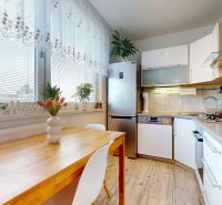 A kitchen in a 3-room apartment with a wooden decor floor, a bright interior full of plants.