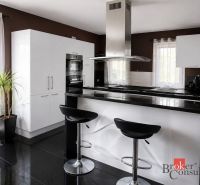 A kitchen in a family house with a bar, black countertops, and white cabinets.
