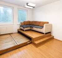 Living room with a corner sofa and a pull-out bed in a 2-room apartment, floor with wood decor.