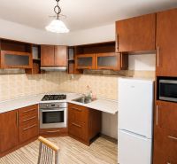 A kitchen in a 2-room apartment with wooden cabinets and appliances.