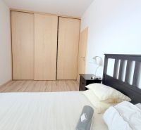 Bedroom in a 2-room apartment with a double bed, built-in wardrobe, and a lamp.
