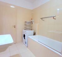 Bathroom with a bathtub, sink, washing machine, and vents in a 2-room apartment.