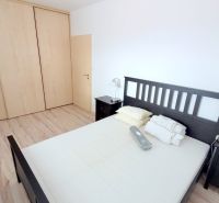 A bedroom with dark furniture and a wood-patterned floor in a 2-room apartment.