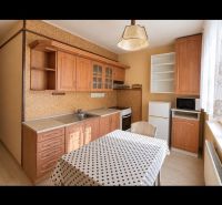 The kitchen in the 2-room apartment has a wooden-patterned floor and a polka dot tablecloth.