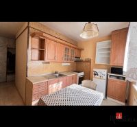 A kitchen with wooden decor, cabinets, and a dining table in a two-room apartment.