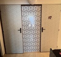 Wallpapered doors in the interior of a 2-room apartment with a wood-patterned floor.