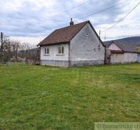 A family house in the village of Volica with an adjacent green garden and a hilly backdrop.