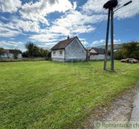 A family house in the village of Volica with a green lawn, an electric pole, and a parked car.