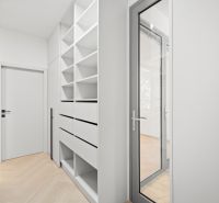 A hallway with built-in shelves and doors in a 4-room apartment with a wooden decor floor.