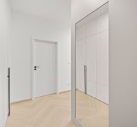 Entrance hall with white built-in wardrobes and wood-patterned flooring in a 4-room apartment.