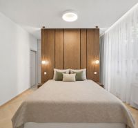 A bedroom in a 4-room apartment with wooden paneling, a light panel, and large windows.