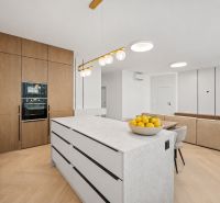 A kitchen in a 4-room apartment with a wood-patterned floor and fruit on the island.