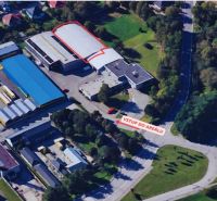 Aerial view of warehouses and halls in Žilina surrounded by greenery and buildings.