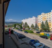 Street of the May Uprising of the Czech People in Brezno with apartment buildings and parked cars.