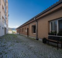 The area with interlocking paving stones between the buildings on the street Májového povstania českého ľudu in Brezno.