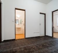 An entrance hall with dark tiles in a 2-room apartment, bathroom in the background.