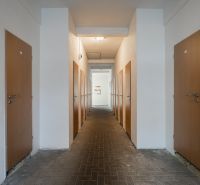 A corridor with symmetrically arranged doors, tiled floor, simple lighting.