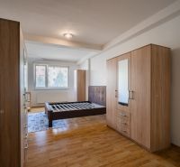 Bedroom in a 2-room apartment with a bed, wardrobes, and a floor with a wooden decor.
