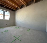 An empty room with a wooden ceiling, plastered walls, a window in a family house.