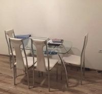 Glass dining table with white chairs on a floor with wood decor.