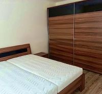 Bedroom in a 2-room apartment with a bed and a large wardrobe, floor with wooden decor.