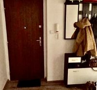 Entrance hallway in a 2-room apartment with wood-patterned flooring, a coat rack, and a mirror.
