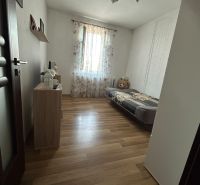 A room in a 2-room apartment with a wooden decor floor and simple furnishings.