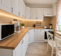 A kitchen in a three-room apartment with a wooden decor floor and white furniture.
