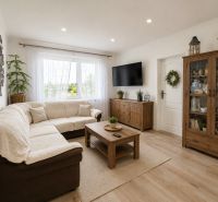 Living room in a 3-room apartment with a comfortable sofa and a wooden-patterned floor.