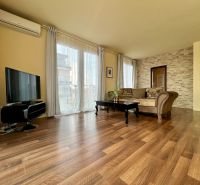 Living room in a two-room apartment with a wooden decor floor, a television, and a comfortable sofa.