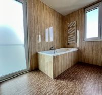 A bathroom in a 2-room apartment with a bathtub, a window, and glass doors.