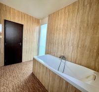A bathroom with a bathtub and tiles in a 2-room apartment.