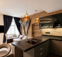 A kitchen in a 2-room apartment with a brick wall and dark-colored curtains.