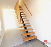 A hallway in a 2-room apartment with an open staircase and a wooden decor floor.
