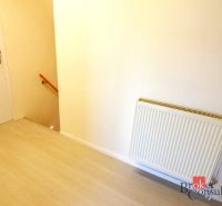 A hallway with a wooden decor floor, a radiator, and a staircase in a 2-room apartment.