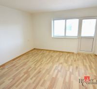 A bright room with wood-decor flooring in a 2-room apartment with access to a balcony.