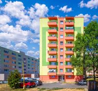 Colorful apartment buildings on Sládkovičova Street in Fiľakovo with parking and greenery.