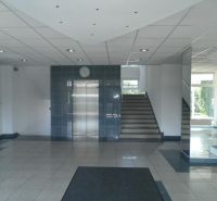 Offices with an elevator and staircase, mirrors reflecting light, tiled floor.