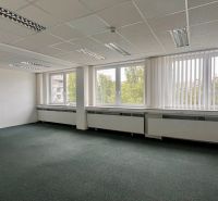 Empty offices with large windows and carpeted floors.