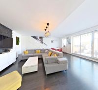 Living room in a 3-room apartment with a wooden decor floor and a television on a dark wall.