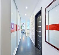 A hallway in a 3-room apartment with a wooden decor floor and glass doors.