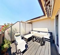 The balcony of a 3-room apartment on Krátka Street in Senec with blooming plants and wooden decor.