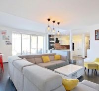 Living room in a three-room apartment with a wooden decor floor and red chairs.