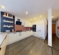 A kitchen in a 3-room apartment with a wooden decor floor, shelves, and a large window.