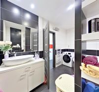 A bathroom in a 3-room apartment with black and white tiles, a washing machine, and a sink.