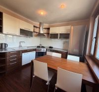 A kitchen with white cabinets, a wooden decor floor, and a dining table.